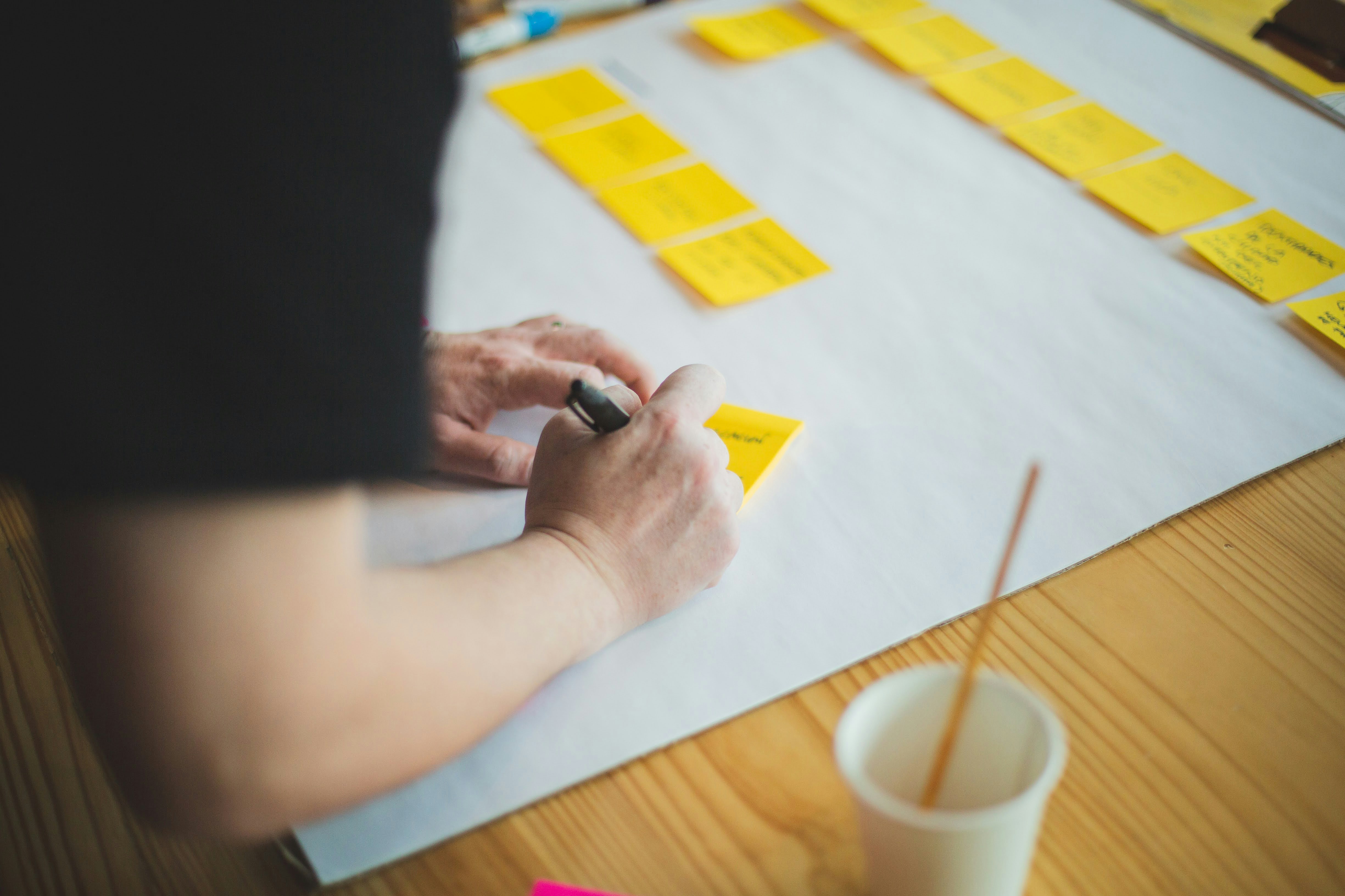 Person, die ein PostIt für eine PostIt-Wand anfertigt