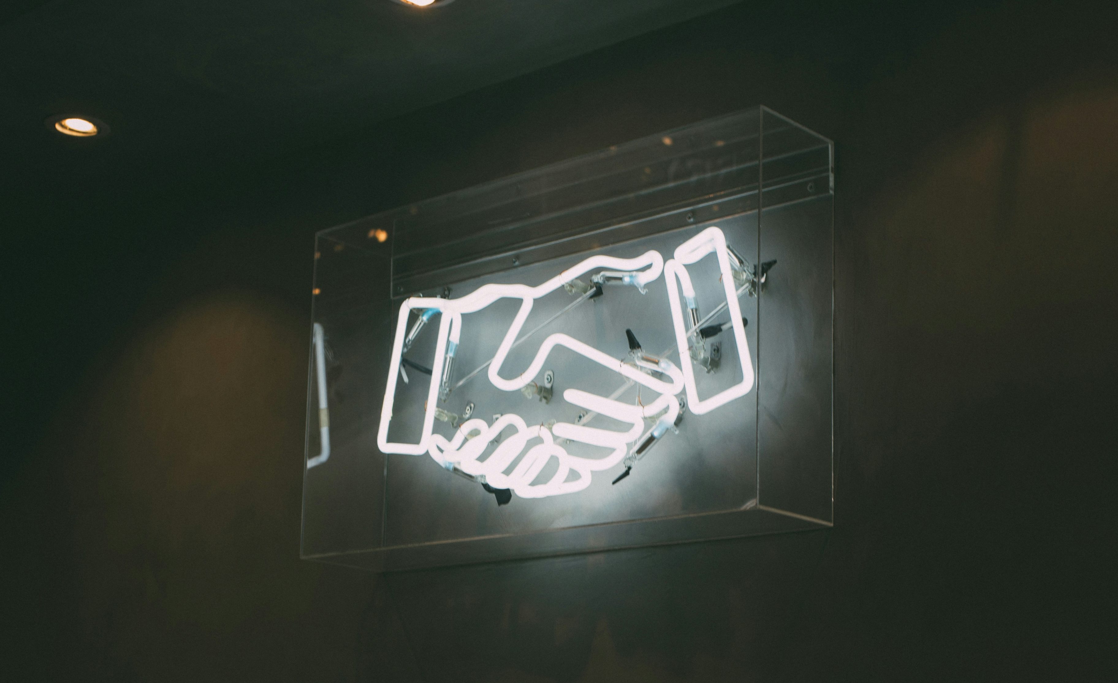 Neonschild, das ein Händeschütteln darstellt